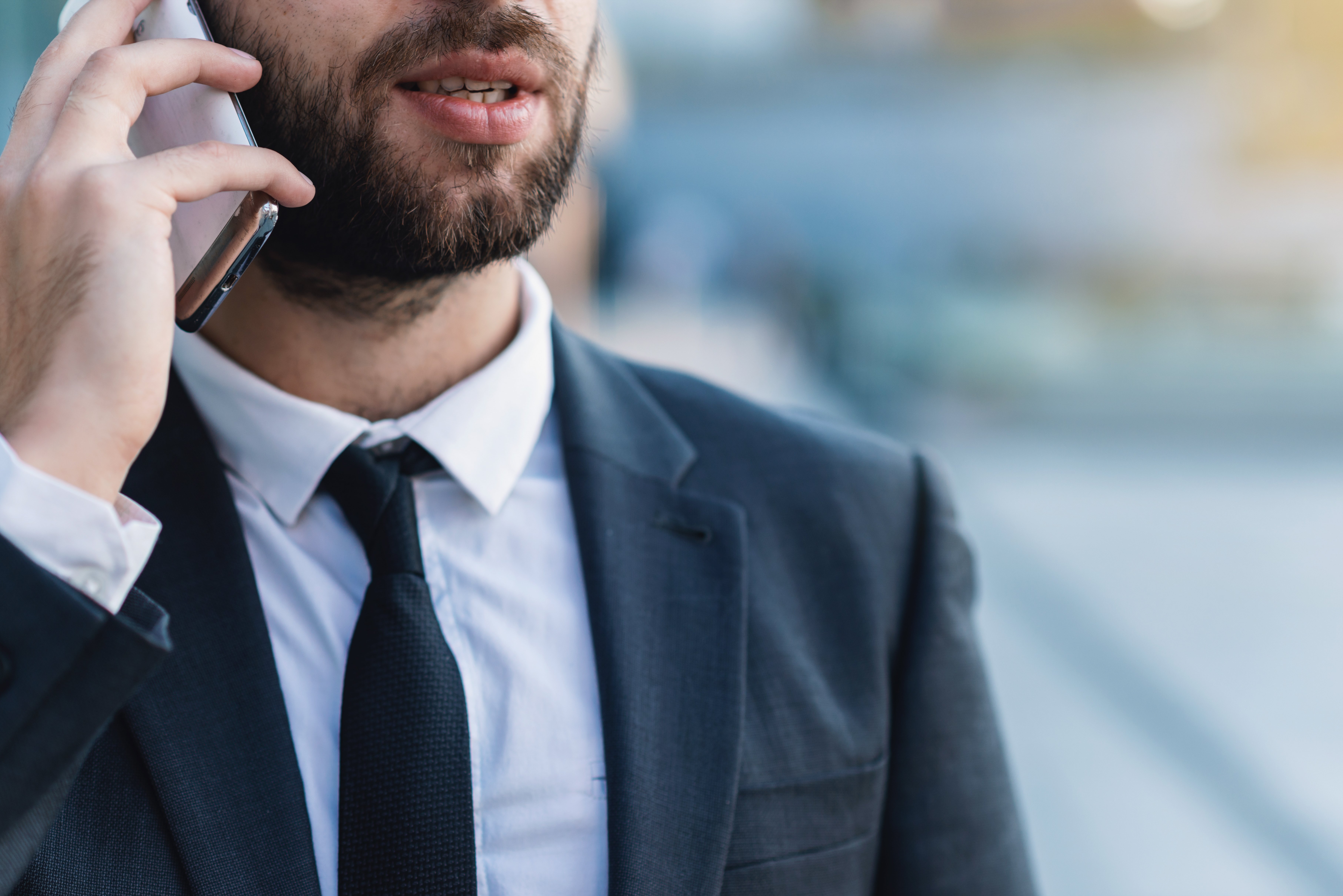 close-up-businessman-talking-on-smartphone-against-2023-11-27-05-25-35-utc